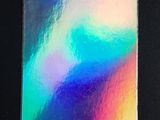 un gros plan de la quatrième de couverture d'un cahier aux couleurs de l'arc-en-ciel posé sur une surface noire