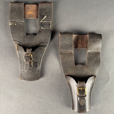 pair of old leather shoes with metal buckles on a gray surface