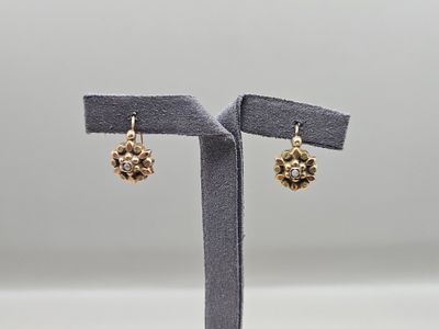 une paire de boucles d'oreilles posée sur un présentoir, sur fond gris