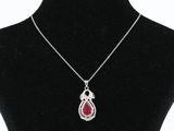 a silver necklace with a red tear shaped pendant on a black mannequin