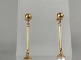 a pair of pearl and gold earrings on a white stand