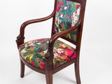 un gros plan d'une chaise en bois dont l'assise est recouverte d'un tissu coloré