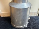 a silver vase with umbrellas in it on the floor