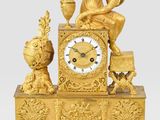 une horloge en or surmontée d'une statue représentant un homme assis