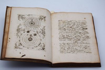un livre ouvert avec une écriture dessus, posé sur une table