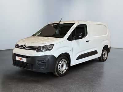 La camionnette blanche est garée dans une pièce au sol gris