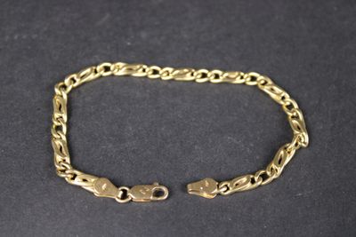 gros plan d'un bracelet en or sur une surface noire
