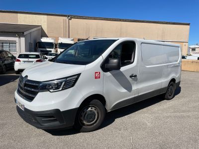 une camionnette blanche garée sur un parking, avec d'autres véhicules en arrière-plan