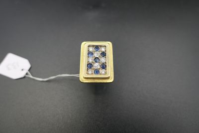 un gros plan d'une bague en or sertie d'un diamant bleu sur une surface noire