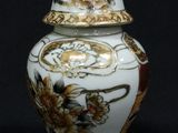 a white and gold vase with a lid on a black background