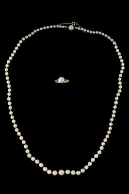 un ensemble composé d'un collier et d'une bague en perles blanches, sur fond noir