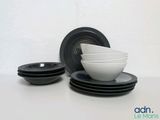 plusieurs bols et assiettes noirs et blancs posés sur une table blanche