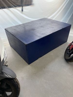une boîte bleue posée par terre à côté d'un scooter