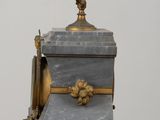 a silver and gold clock sitting on top of a table