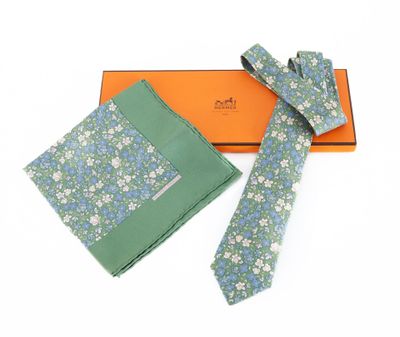 Coffret cadeau comprenant une cravate et une pochette à motifs floraux bleus et verts, présenté dans une boîte orange