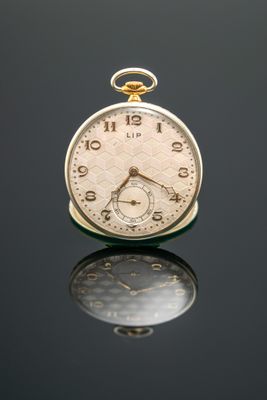 un gros plan d'une montre de poche posée sur une surface réfléchissante