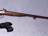 un fusil et un pistolet posés sur une table blanche, sur fond blanc