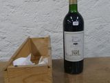 une bouteille de vin posée sur une table à côté d'une caisse en bois
