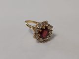 un gros plan d'une bague ornée d'une pierre rouge entourée de petites pierres blanches