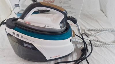 a black and white steam iron sitting on a bed