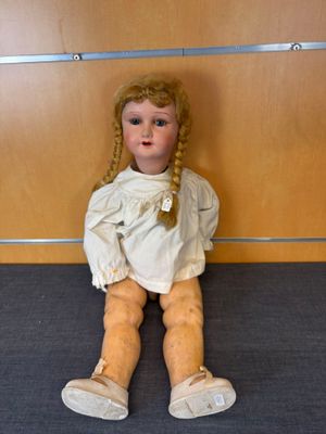 une petite poupée assise par terre devant un mur
