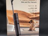 the box of a vacuum cleaner with a dog sitting on the floor