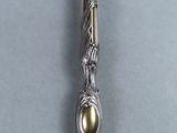 an image of a silver spoon with a gold bead on it