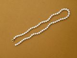 a close up of a white beaded necklace on a brown surface