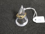 une bague en or posée sur un présentoir transparent, à côté d'une étiquette de prix