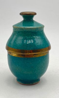a blue vase with a gold rim sitting on a white surface