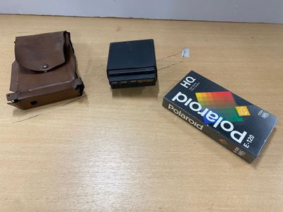 un appareil photo Polaroid posé sur une table à côté d'un portefeuille