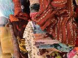 une femme assise sur un lit, avec une pile de vêtements à côté d'elle