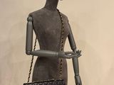 mannequin holding a black chanel bag on display in front of a mannequin