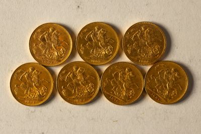 six souverains d'or empilés les uns sur les autres sur une surface blanche