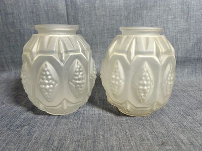 une paire de vases en verre blanc posés sur un tissu gris