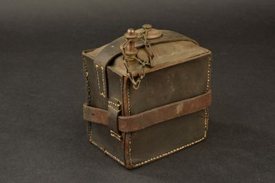 une petite boîte en cuir entourée d'une chaîne, posée sur une table