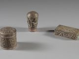 trois objets métalliques argentés posés sur une surface blanche