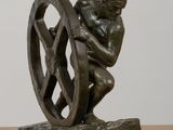 statue of a man holding a wheel on a wooden table