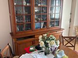 a wooden china cabinet in the middle of a dining room table