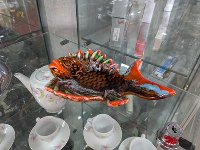 une vitrine en verre sur laquelle sont posés un poisson, des tasses et des soucoupes