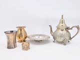 a silver tea pot, a silver cup, and a silver plate