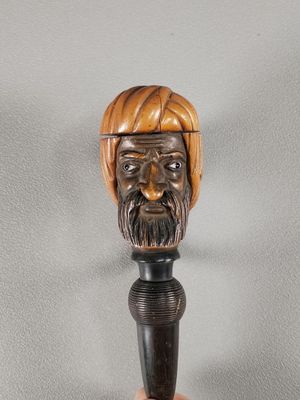 tête d'homme en bois sculptée à la main, coiffée d'un turban, posée sur une canne