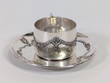 a silver cup and saucer on a saucer on a plate