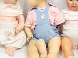 three dolls sitting next to each other on a white surface