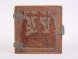 carvings on the back of a leather book with a silver handle