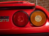 the rear end of a red sports car parked in front of a brick wall