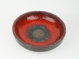 a red bowl with a black rim on a white surface