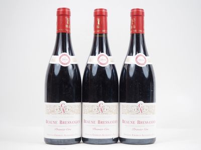 trois bouteilles de vin rouge posées l'une à côté de l'autre sur une surface blanche