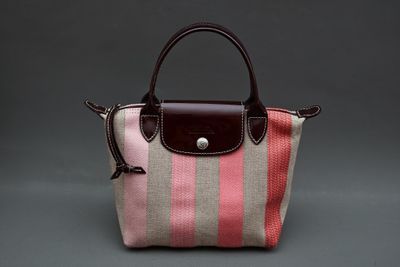 un sac à main rayé rose et beige avec une anse marron
