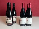 three bottles of red wine are lined up on a counter